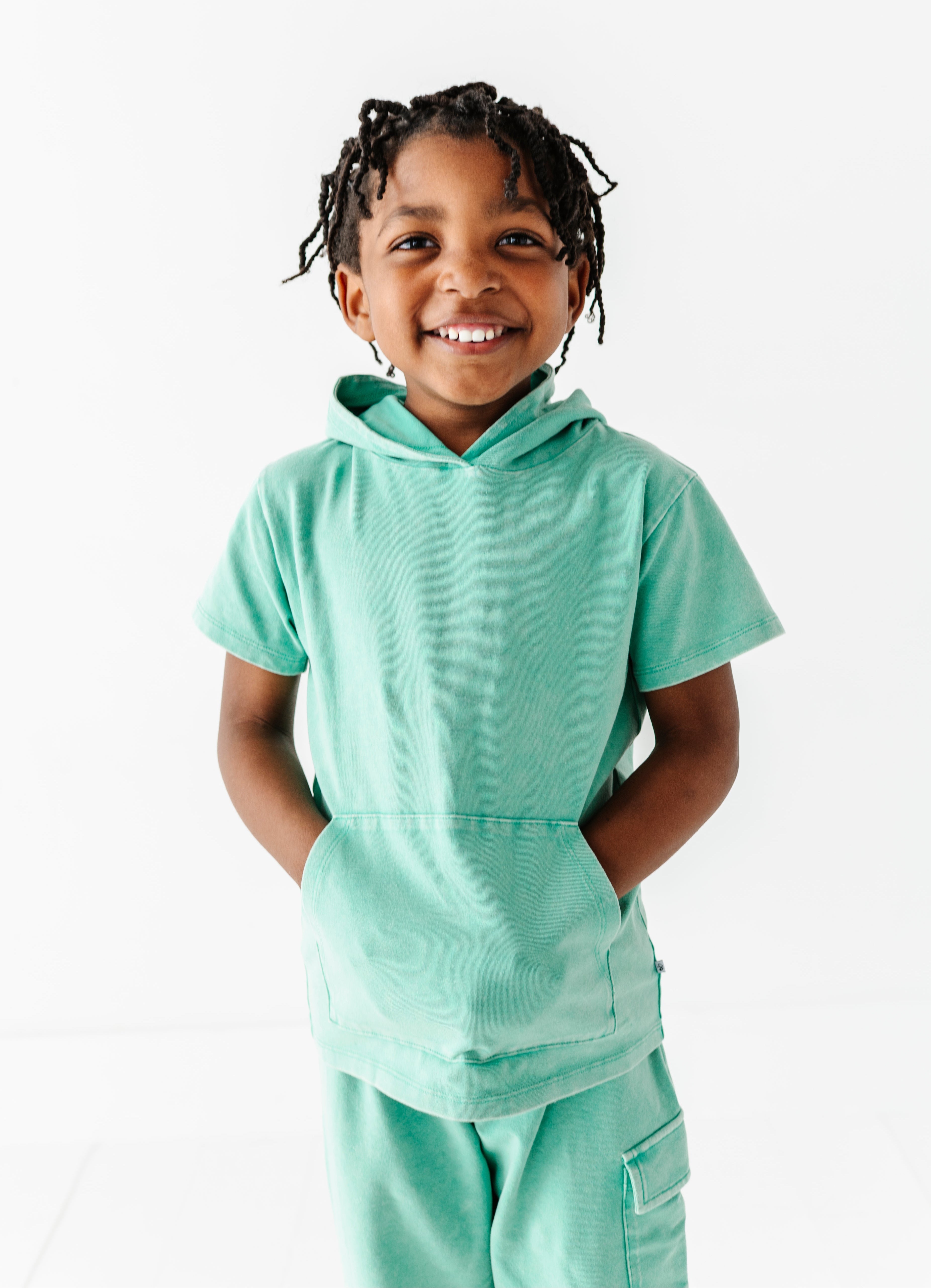 Child wearing a light green hoodie and pants on a white background